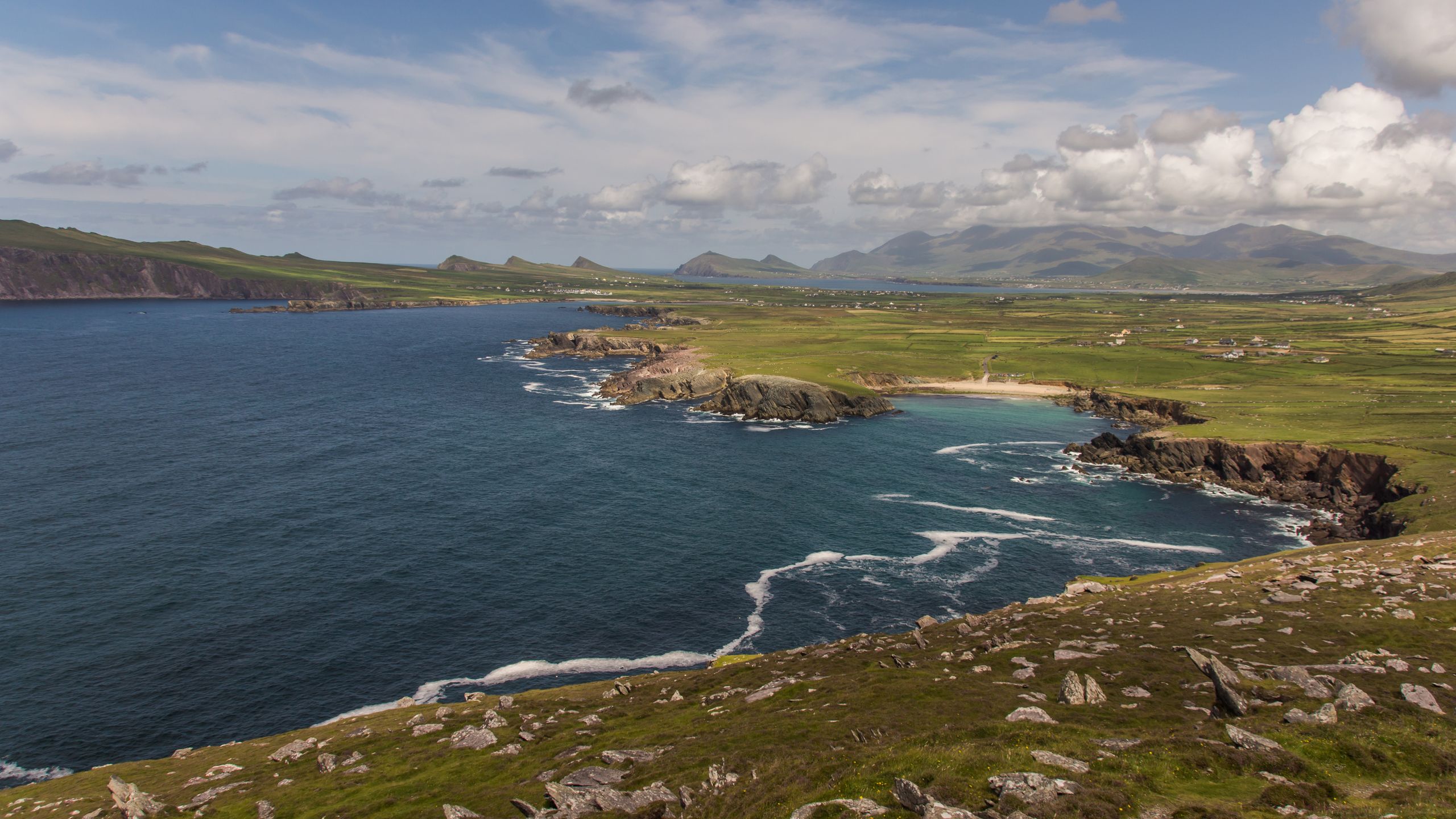 Breathtaking view of the Dingle Peninsula coast with green landscapes and rugged cliffs in Ireland.